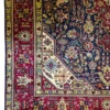 Close-up corner view of a camel and terracotta Persian Tabriz rug highlighting the dense multi-guard border and clean hand-bound edge finish.