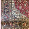 Close-up corner view of a Persian Tabriz rug highlighting the intricate navy floral border, cream guard lines, and flat hand-bound edge finish.