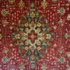 Macro shot of the dense hand-knotted wool pile on an Iranian Tabriz rug, highlighting the fine geometric floral outlines of the central star medallion.