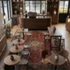 Boutique lounge corner with two tan leather club chairs and a small round table on a traditional red and cream Tabriz area rug.