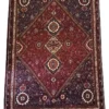 Full overhead view of a 6' 5" x 9' 10" hand-knotted Iranian wool rug with a vertical row of three diamond medallions on a plum and deep red field.
