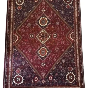 Full overhead view of a 6' 5" x 9' 10" hand-knotted Iranian wool rug with a vertical row of three diamond medallions on a plum and deep red field.