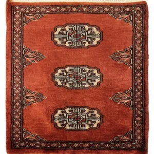 Overhead view of a 1' 6" x 1' 10" hand-knotted Pakistan Bokhara wool rug in rust red with three central ivory and black gul medallions.