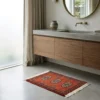 Luxury modern bathroom with concrete counters and walnut cabinetry, featuring a small rust-colored Bokhara accent rug on a polished concrete floor.