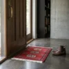 Bright modern entryway with a walnut door and concrete floors, featuring a small ruby-red Pakistan Bokhara rug as a vibrant floor accent.