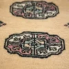 Macro shot of the dense hand-knotted wool pile on a gold Bokhara rug showing the intricate geometric gul motif and soft texture.