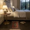 Serene modern bedroom with dark wood floors and a brass nightstand, featuring a small rose-colored Jaldar rug placed beside the bed.