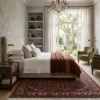 6' 7" x 10' 0" Persian Hoseinabad wool rug partially placed under a luxury upholstered bed in a cozy neutral bedroom.