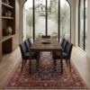Sophisticated dining room featuring a long wooden table and black upholstered chairs, centered over an intricate 6x10 Kashan area rug.