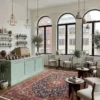 High-end modern coffee shop with walnut bar counters and bistros, anchored by a large red and navy Kashan Persian rug under wood and upholstered seating.