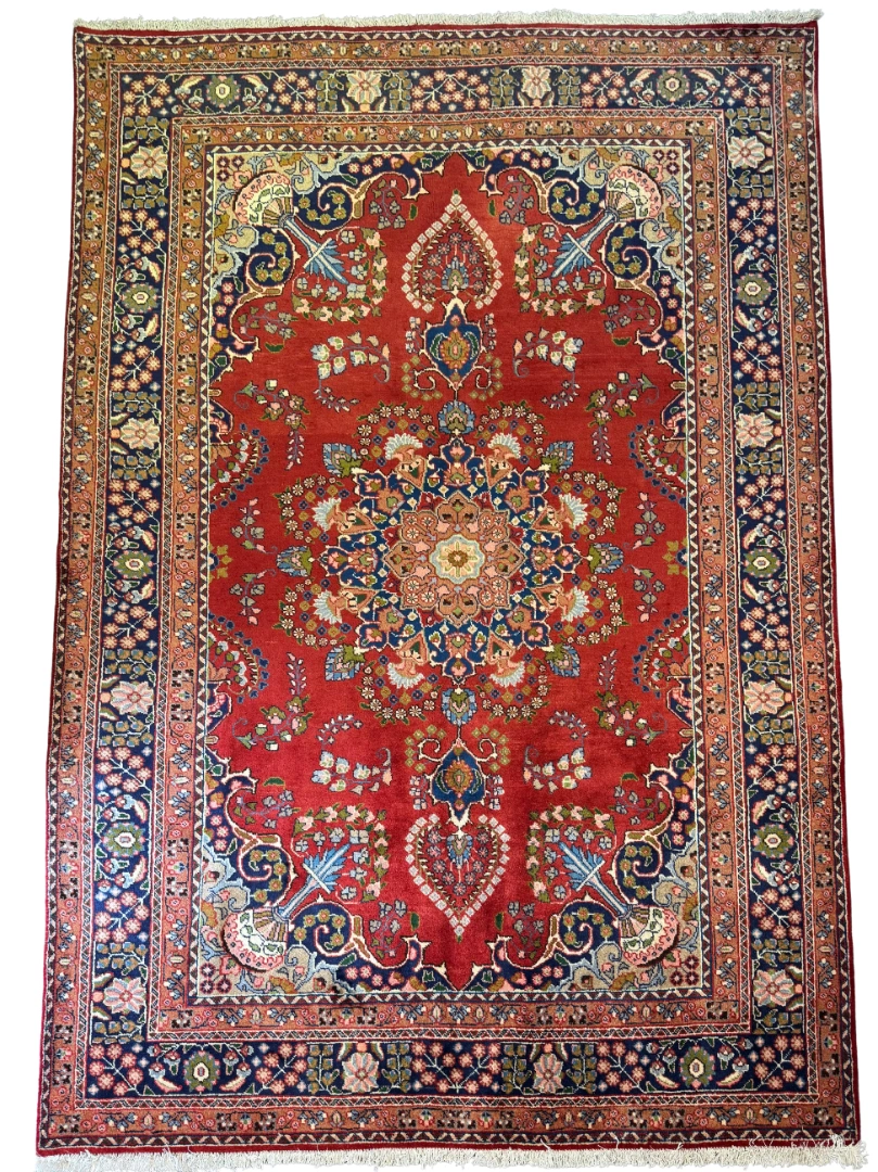 Full overhead view of a 6' 6" x 9' 6" hand-knotted Iranian Sabzevar wool rug featuring a large circular floral medallion on a vibrant red field with navy blue borders.