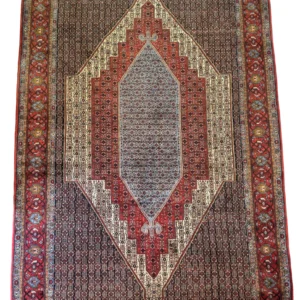 Full overhead view of a 6' 7" x 9' 10" hand-knotted Iranian Seneh wool rug featuring a large stepped diamond medallion in slate blue, red, and cream on a dark field.