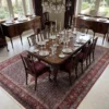 Stately formal dining room with a long mahogany table and velvet upholstered chairs, centered over an intricate 7x10 Seneh Persian rug.