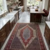 Upscale modern kitchen with warm walnut cabinetry and a central island, anchored by a large red and blue hand-knotted Seneh rug runner.