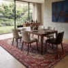 Sophisticated dining room featuring a long wooden table and beige upholstered chairs, centered over an intricate 7x10 Tabriz area rug under floor-to-ceiling windows.