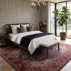 Peaceful primary bedroom with a mahogany bed frame and white linens, anchored by an intricate red Tabriz Persian rug under a classic chandelier.