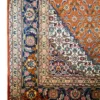 Close-up of the corner, floral border, and ivory fringe on a Persian Mahi wool area rug.