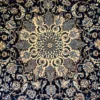 Close-up detail of the central floral medallion and fine wool pile on a hand-knotted Persian Nain rug.