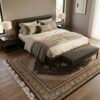 Dark brown and cream Persian Mahi area rug extending from beneath an upholstered bed with a dark bench in a modern master bedroom.