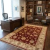 Red and cream Afghan Chobi wool rug in an executive office setting next to a large walnut desk and leather chairs.