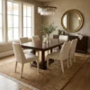Minimalist 6' 7" x 9' 8" Afghan Gabbeh wool rug under a dark wood dining table with six cream upholstered chairs in an organic modern dining room.