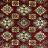 Close-up of geometric diamond medallions and vibrant wool pile on a red Afghan Kazak rug.