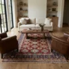 6' 11" x 9' 10" Afghanistan Kazak wool rug styled in a modern living room with a cream sofa and leather armchairs.