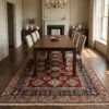 Hand-knotted Afghan Kazak area rug placed under a dark wood dining table with six upholstered chairs in a formal dining room.