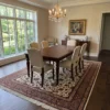 Hand-knotted Persian Arak Golpayegan wool area rug under a dark wood dining table with six cream chairs and a crystal chandelier.