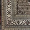 Detailed corner shot of a hand-knotted India Mahi wool area rug showing the beige floral border and fringe.