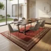 Hand-knotted Indian wool rug placed under a solid walnut dining table with six cream dining chairs in a sunlit dining space.