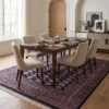 7' 3" x 9' 11" Pakistan Bokhara wool rug in a modern dining room under a walnut dining table with six cream chairs.