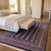 Pakistan Bokhara wool rug extending beneath a king-size bed with a neutral bench in a serene, modern bedroom.