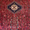 Close-up of the central diamond medallion, stylized bird motifs, and fine wool pile on a red Persian Abadeh rug.