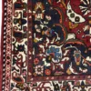 Detailed corner view of a Persian Bakhtiar wool rug showing the dark navy spandrel, ivory border band, and white fringe.