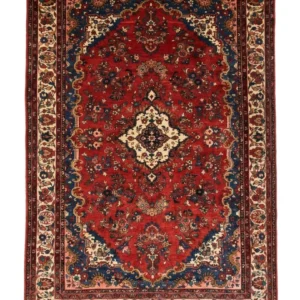 Full overhead view of a 6' 11" x 10' 4" hand-knotted Persian Hamedan wool rug featuring a rich red field, cream central medallion, navy spandrels, and a floral cream border.