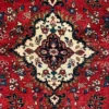 Close-up of the cream and navy central medallion and plush wool pile on a red Persian Hamedan carpet.