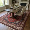 Hand-knotted red and navy Persian Hamedan wool area rug under a dark wood dining table with six beige chairs.