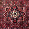 Close-up detail of the central 8-pointed star medallion on a hand-knotted Persian Hoseinabad wool area rug.