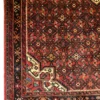 Detailed corner view of a Persian Hoseinabad wool rug showing cream spandrels, a dark geometric border, and white fringe.