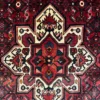 Close-up of the central star medallion and all-over floral lattice pattern on a red Persian Hoseinabad wool rug.