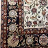 Detailed corner view of a Persian Mashhad wool rug showing the dark navy floral border and white fringe edge.