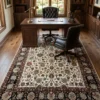 Cream and navy Persian Mashhad area rug placed in an executive home office under a mahogany desk and dark leather chairs.