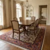 Traditional Persian Sarough wool rug styled under an extendable mahogany dining table with six beige upholstered chairs and a chandelier.