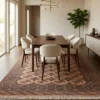 Hand-knotted Persian Turkaman area rug placed beneath a walnut dining table with six cream bouclé chairs.