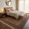 Dusty rose Persian Turkaman wool rug extending beneath a modern leather bed in a serene master bedroom.