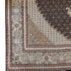Detailed corner view of a Persian Mahi wool rug showing the sage green floral border, stepped cream spandrel, and tassel fringe.