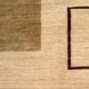 Close-up of the natural hand-spun wool pile showing an olive-green color block and an espresso geometric frame line on an ivory Afghan Choobi rug.