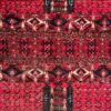 Close-up of columnar cartouches, serrated diamond bands, and fine hand-knotted wool pile on a red Afghan Torkman rug.