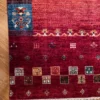 Detailed corner view of an Afghan Uzbek wool runner rug showing deep red pile, checkered geometric blocks, and multicolored wrapped tassel fringe.